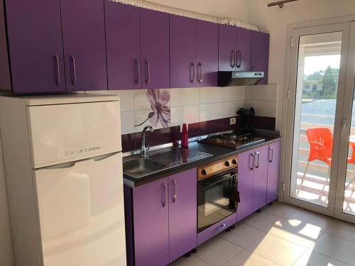 a purple kitchen with a sink and a refrigerator at Palma Apartments in Durrës