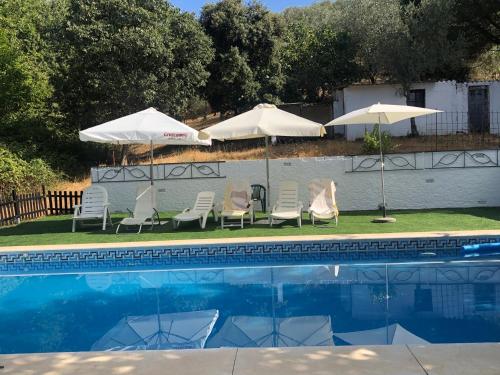 コンスタンティナにあるCasa rural en Constantinaのパラソル2本、芝生の椅子2脚、パラソル2本が備わるプールを併設しています。