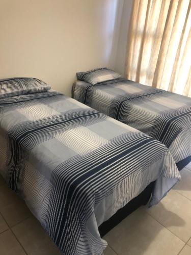 duas camas sentadas uma ao lado da outra num quarto em A Coastal/island experience at a Large 2 bed apartment at a Crystal Lagoon Estate. em Pretoria