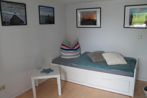 Cama en habitación con mesa y fotografías en Lutzi´s Ferienwohnung, en Rostock