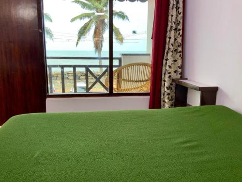 a bedroom with a green bed and a view of the ocean at Mermaid Island Beach Resorts in Puducherry