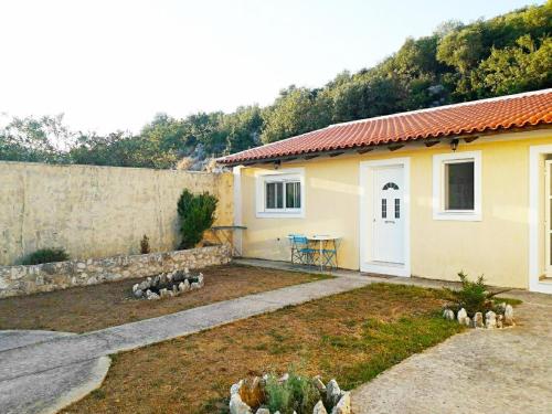 a small yellow house with a table in a yard at Ionian Balcony - Davgata in Dhavgáta