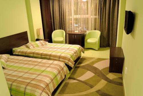 a hotel room with two beds and a table and chairs at Hotel Grim in Craiova