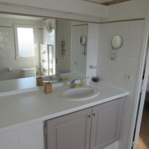 une salle de bain blanche avec un lavabo et un miroir dans l'établissement Résidence les Grimaudières, à Grimaud