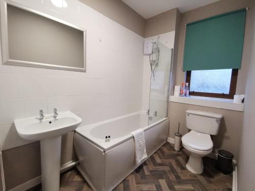 a bathroom with a toilet, sink, and bathtub at Friars Wynd Hotel in Stirling