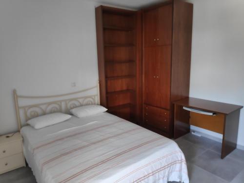 a bedroom with a bed and a wooden cabinet at Melistalia appartment 1 in Nea Michaniona