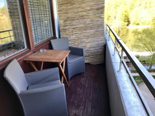 balcón con mesa de madera y 2 sillas en Appartement JZ, en Malente