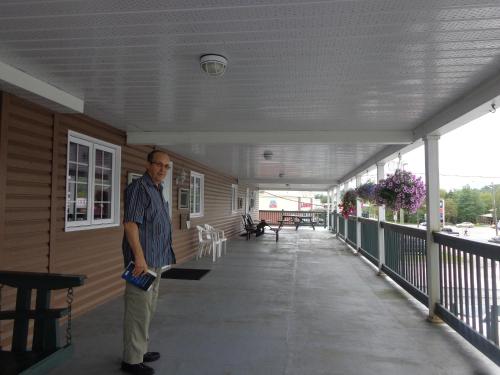 a man standing on the porch of a building at Happy Motel in Edmundston