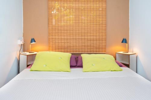 a bedroom with a white bed with two yellow pillows at Rusty Pelican - Lazy Lizard Container Home. in La Gaulette