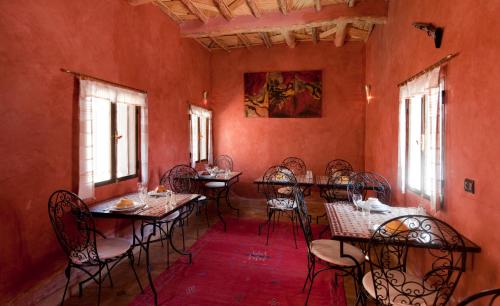 a dining room with tables and chairs and windows at Kasbah La Cigogne in Aït Ben Haddou