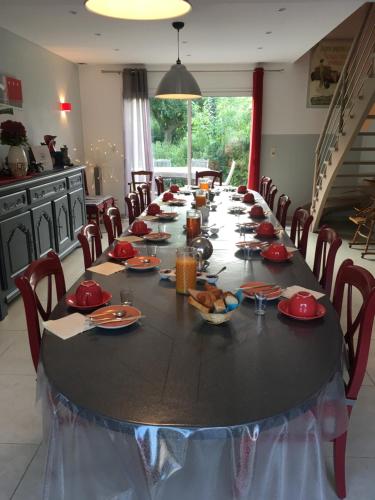 Le Clos des Pommiers في Tracy-sur-Mer: طاولة طويلة في مطبخ عليها أطباق حمراء