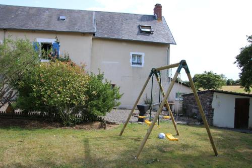a swing set in a yard in front of a house at La Parisiere in Gavray