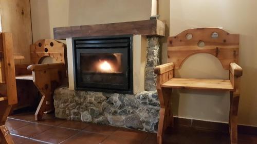a fireplace in a room with two wooden chairs at Casa Curnet in Balme