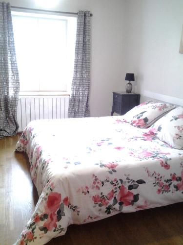 a bedroom with a bed with a floral bedspread at La Parisiere in Gavray