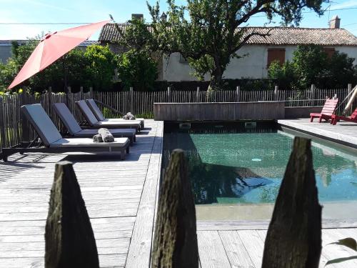 - une piscine avec des chaises longues et un parasol à côté dans l'établissement Le Relais du Haras, à Champagné-Saint-Hilaire