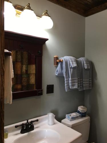 a bathroom with a sink and a toilet with towels at Warrensburg Inn & Suites - 6 Mi to Lake George in Warrensburg