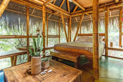 a bedroom in a tree house with a bed and a table at Universo Pol Bamboo Hostel in Morro de São Paulo