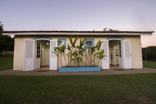 a small house with white doors and a plant at Hotel Alto da Boa Vista in Analândia