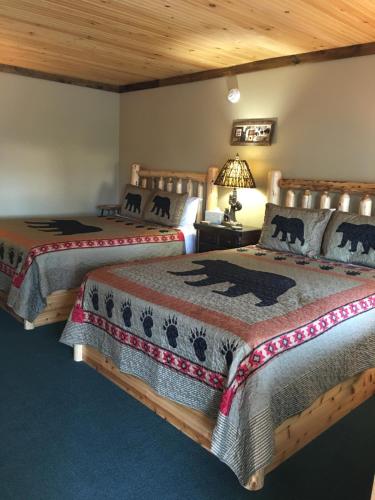 two beds in a room with wooden ceilings at Warrensburg Inn & Suites - 6 Mi to Lake George in Warrensburg