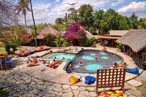 a group of people sitting around a pool at a resort at Begadang in Gili Air
