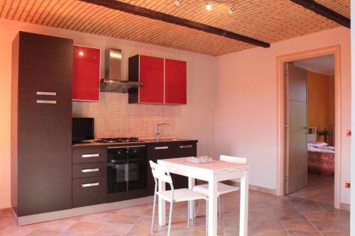 a kitchen with red cabinets and a white table and chairs at I Boidi in Nizza Monferrato