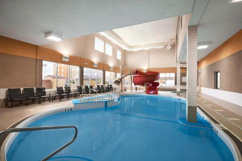 - une grande piscine dans une grande pièce avec des chaises dans l'établissement Days Inn & Suites by Wyndham Winnipeg Airport Manitoba, à Winnipeg