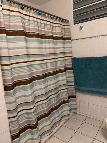 a shower with a striped shower curtain in a bathroom at Los Pinos House in Yauco