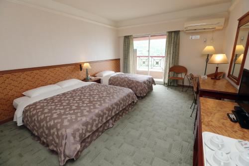 a hotel room with two beds and a television at Hoya Hotel in Wenquan