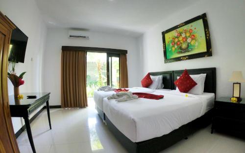 a hotel room with two beds and a desk and a bed sidx sidx at Palm Bamboo Hotel in Nusa Dua