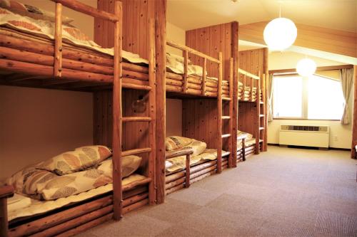 a room with three bunk beds in a house at K's House Hokkaido - Asahidake Onsen Hostel in Higashikawa