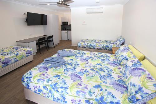 1 dormitorio con 2 camas y escritorio. en Reef Gardens Motel, en Proserpine