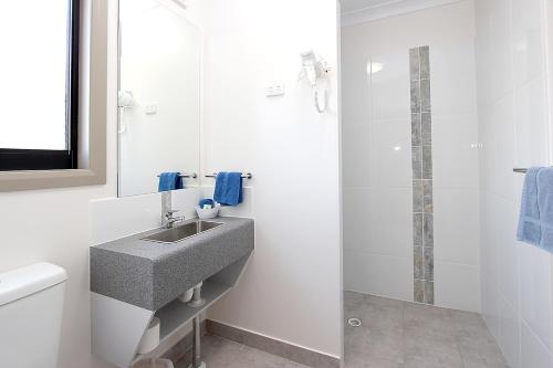 W łazience znajduje się umywalka i prysznic. w obiekcie Reef Gardens Motel w mieście Proserpine