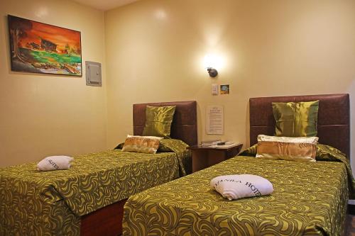 a room with two beds with pillows on them at Fj Manila Hotel in Daraga