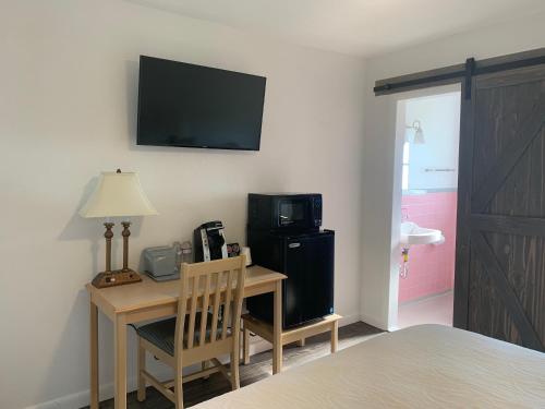 a room with a desk with a microwave and a television at Cape Motel in Cape Charles