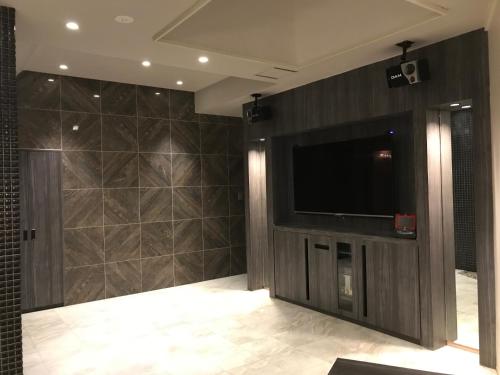 a living room with a flat screen tv and a wall at Hotel Gaudium (Adult Only) in Kuki