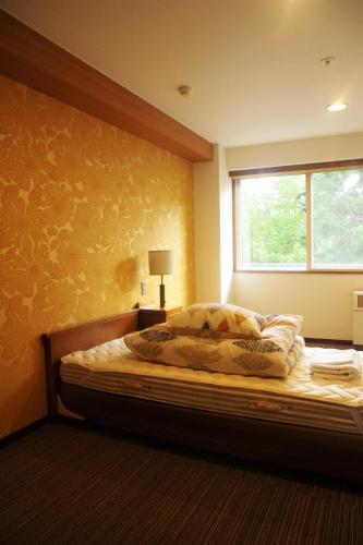 a bedroom with a large bed with a window at K's House Hokkaido - Asahidake Onsen Hostel in Higashikawa