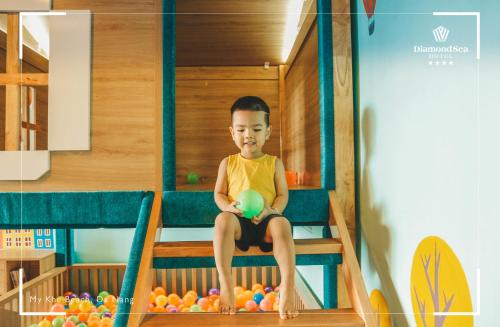 a young boy sitting on a bunk bed with a ball at Diamond Sea Hotel in Da Nang