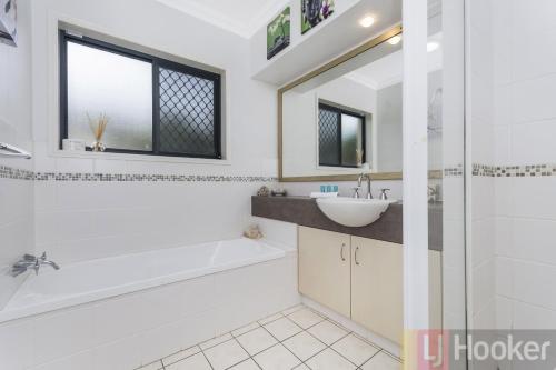 a bathroom with a white tub and a sink and a bath tubermottermottermott at Oceania Beach Paradise LJHooker Yamba in Yamba