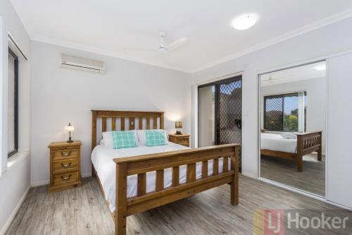 a bedroom with a bed and a mirror and a tub at Oceania Beach Paradise LJHooker Yamba in Yamba