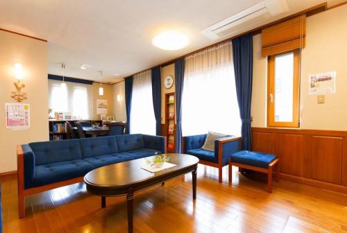 Urayasu Guesthouse 浦安ゲストハウス في Urayasu: غرفة معيشة مع أريكة زرقاء وطاولة