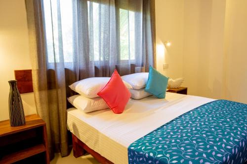 a bedroom with a bed with pillows and a window at Villa Agoura Grand Negombo in Negombo