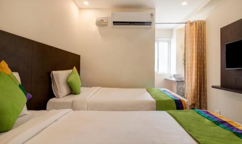 a hotel room with two beds and a television at Treebo Sls Grand in Tirupati