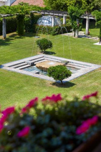 a fountain in a park with flowers in the grass at Hotel Villaguarda Prosecco Area in Follina