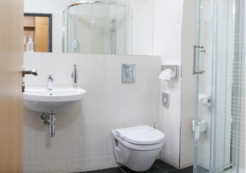 La salle de bains est pourvue de toilettes, d'un lavabo et d'une douche. dans l'établissement Hotel Port Doksy, à Staré Splavy