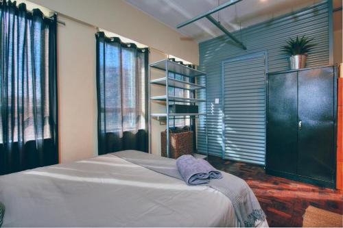 a bedroom with a bed and a book shelf at Cozy, Modern Living in Maboneng: 104 in Johannesburg