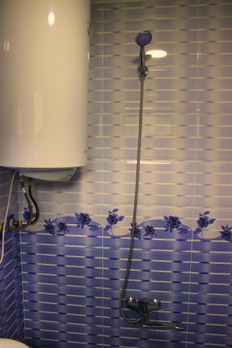 a blue tiled bathroom with a shower with purple flowers at Guest House "Oasis" in Khulo