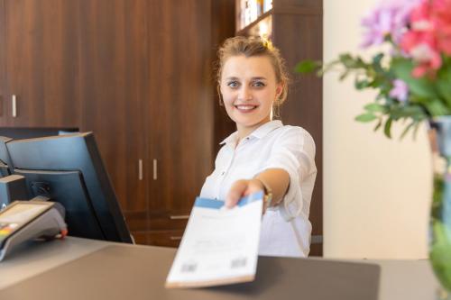 a woman sitting at a desk holding a piece of paper at Trip Inn Hotel Messe Westend in Frankfurt/Main