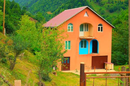 an orange house with a red roof on a hill at Guest House "Oasis" in Khulo