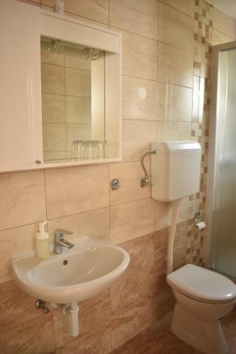 a bathroom with a sink and a toilet and a mirror at Guest House Mićin in Vodice