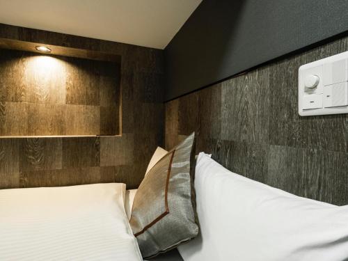 a bedroom with a white bed and a wooden wall at Hotel AreaOne Izumo in Izumo